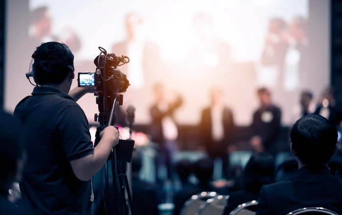 a man capturing video of an event using camera on a stand